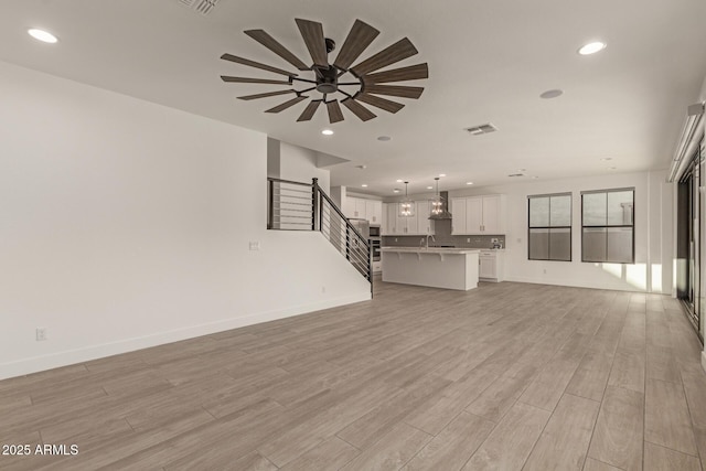 unfurnished living room with light wood-type flooring, baseboards, visible vents, and recessed lighting