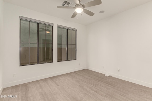 spare room featuring a ceiling fan, visible vents, baseboards, and wood finished floors