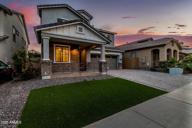 view of front of home with a porch, stone siding, decorative driveway, a front lawn, and board and batten siding