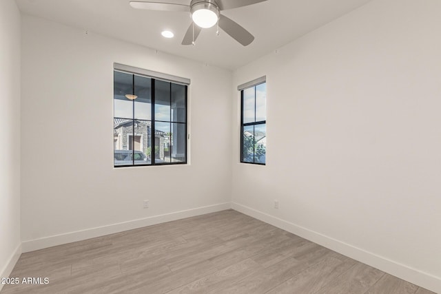 empty room featuring a ceiling fan, light wood-style flooring, and baseboards