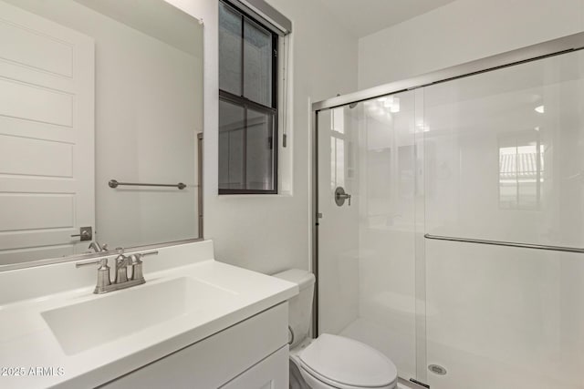 bathroom featuring a shower stall, toilet, and vanity