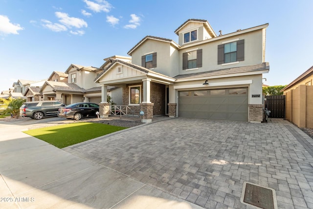 view of front of property featuring decorative driveway, brick siding, an attached garage, a gate, and fence