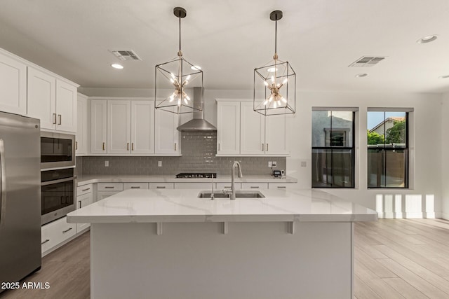 kitchen with visible vents, decorative backsplash, appliances with stainless steel finishes, a sink, and light wood-type flooring