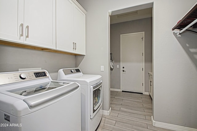 laundry area featuring light hardwood / wood-style flooring, separate washer and dryer, and cabinets