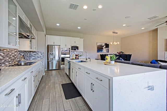 kitchen featuring appliances with stainless steel finishes, sink, an island with sink, decorative light fixtures, and white cabinets