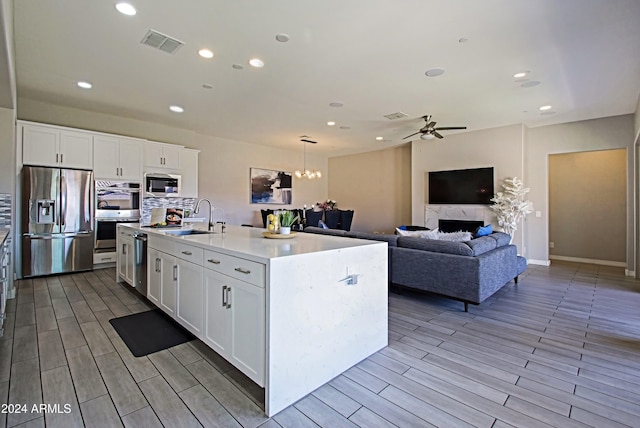 kitchen featuring sink, appliances with stainless steel finishes, a kitchen island with sink, and white cabinetry