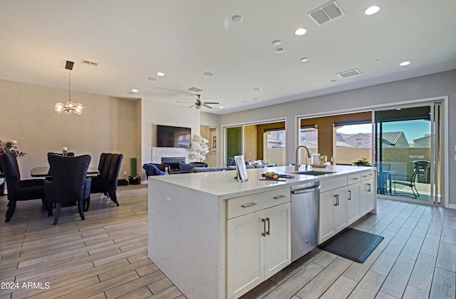 kitchen with white cabinets, hanging light fixtures, a kitchen island with sink, stainless steel dishwasher, and light hardwood / wood-style floors