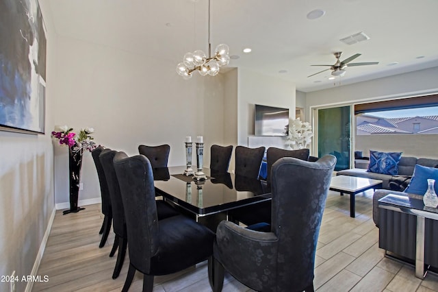 dining room with light hardwood / wood-style floors and ceiling fan with notable chandelier