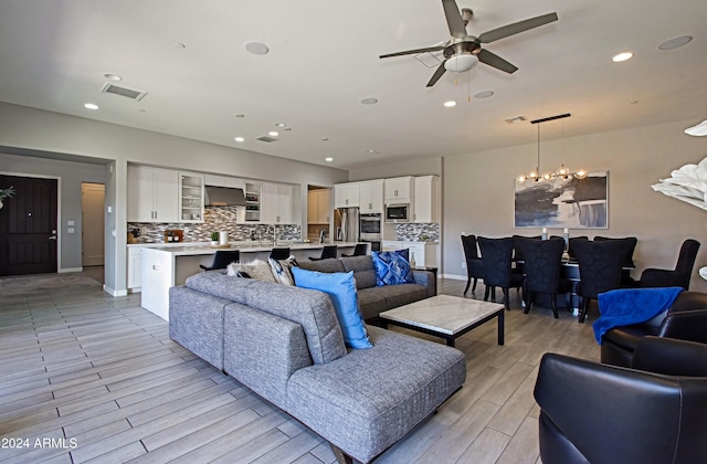 living room with light hardwood / wood-style floors and ceiling fan with notable chandelier