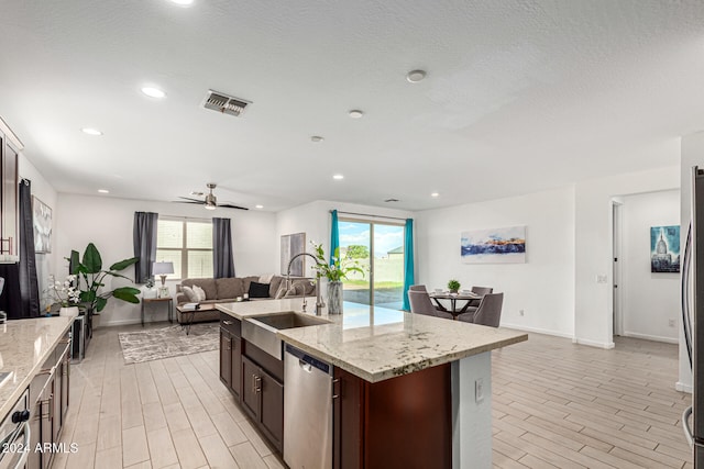 kitchen with stainless steel dishwasher, sink, an island with sink, and a healthy amount of sunlight