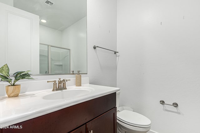 bathroom featuring toilet, vanity, and a shower with shower door