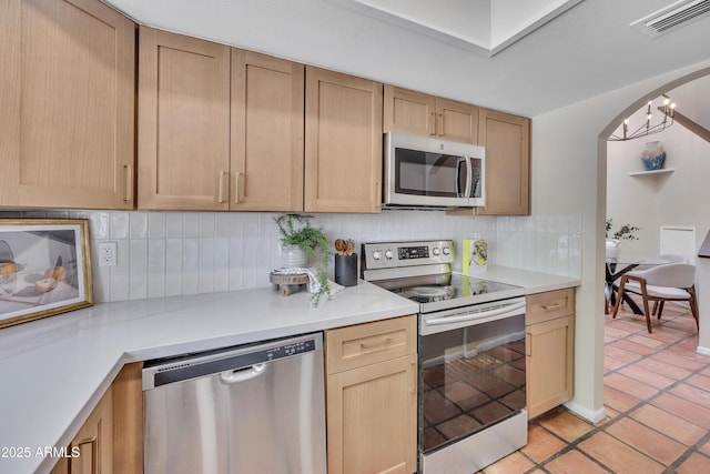 kitchen with visible vents, appliances with stainless steel finishes, tasteful backsplash, arched walkways, and light countertops