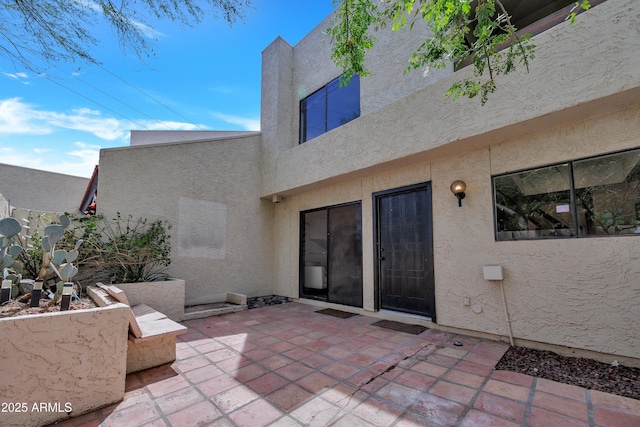 rear view of house featuring stucco siding and a patio area