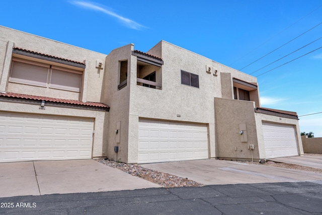 exterior space featuring a garage, stucco siding, and a tiled roof