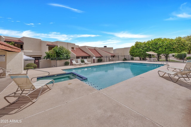 view of swimming pool with a patio area, fence, and a pool with connected hot tub