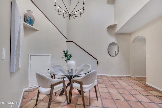 dining room with baseboards, arched walkways, and an inviting chandelier
