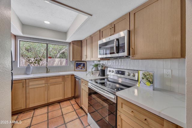 kitchen featuring light countertops, stainless steel appliances, a sink, and tasteful backsplash