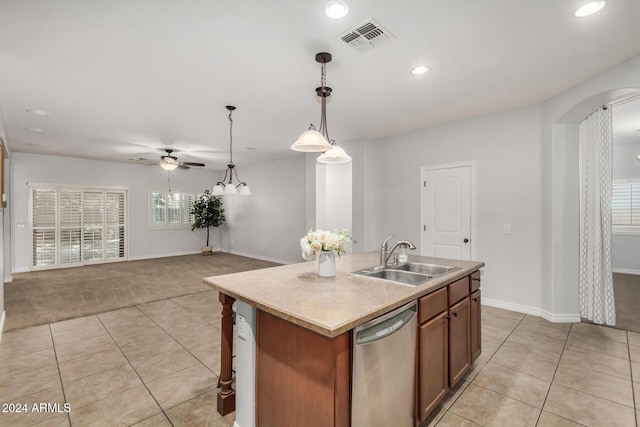 kitchen with light tile patterned flooring, sink, hanging light fixtures, stainless steel dishwasher, and an island with sink