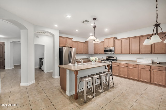 kitchen with stainless steel appliances, a kitchen breakfast bar, a kitchen island with sink, and hanging light fixtures