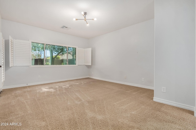 empty room featuring carpet flooring and an inviting chandelier