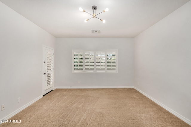 spare room with an inviting chandelier and carpet floors