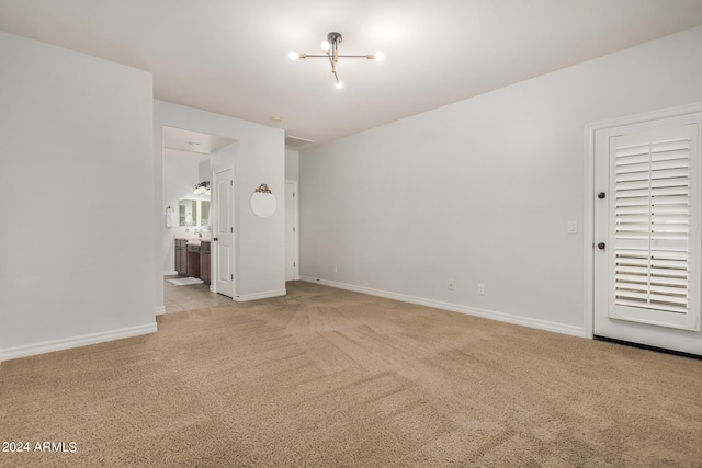 carpeted empty room with a notable chandelier