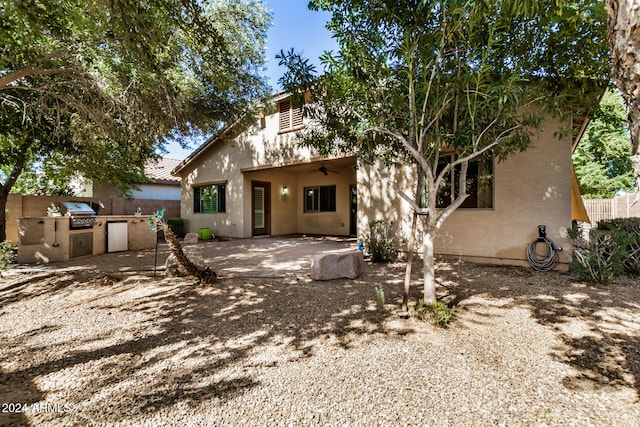 back of property with ceiling fan, an outdoor kitchen, and a patio area