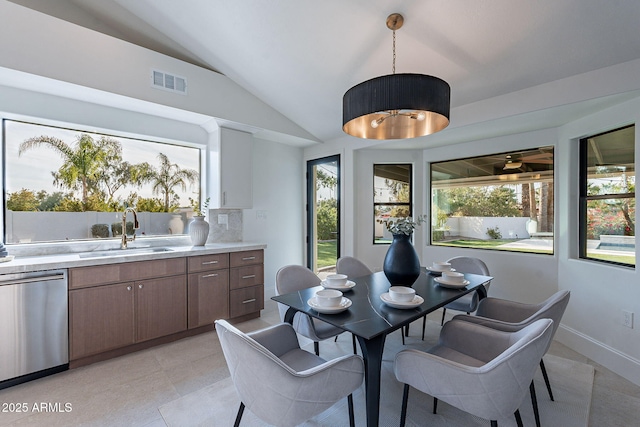 tiled dining space with sink and lofted ceiling