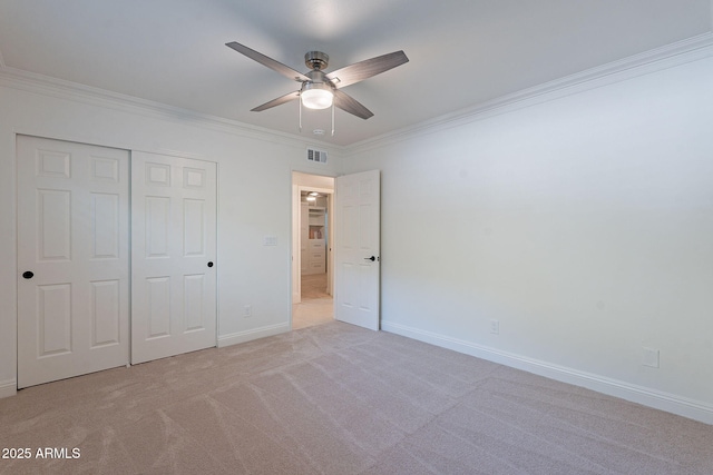 unfurnished bedroom with a closet, ceiling fan, light colored carpet, and crown molding