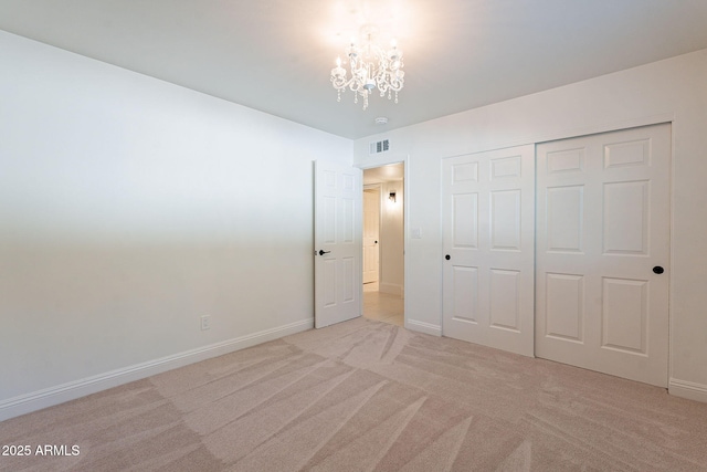 unfurnished bedroom with a closet, light colored carpet, and a notable chandelier