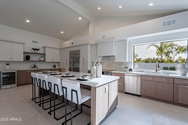 kitchen featuring a kitchen island, white cabinets, wine cooler, and appliances with stainless steel finishes