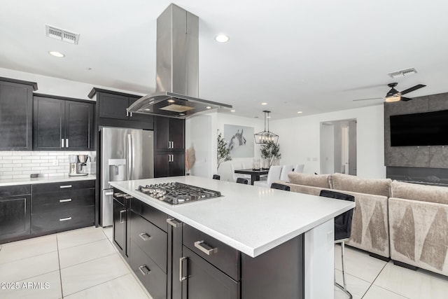 kitchen with appliances with stainless steel finishes, light countertops, visible vents, and island range hood