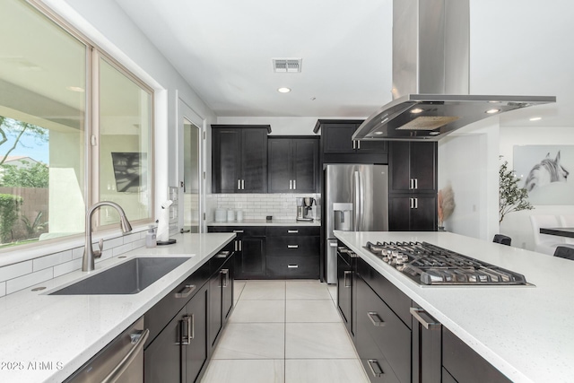 kitchen featuring decorative backsplash, appliances with stainless steel finishes, island exhaust hood, a sink, and light tile patterned flooring