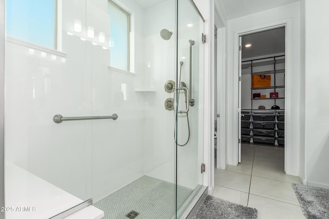 bathroom with a shower stall, a walk in closet, and tile patterned floors