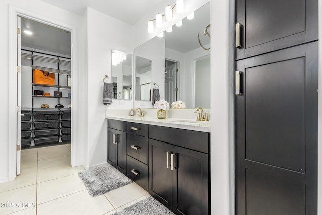 bathroom featuring tile patterned flooring, a sink, baseboards, and double vanity