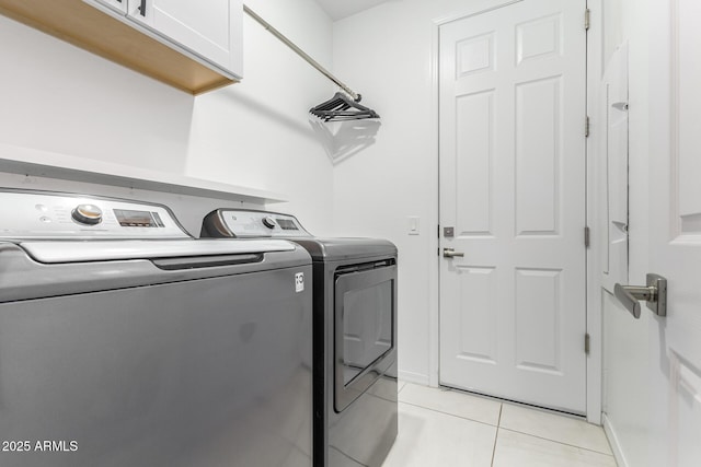 clothes washing area with cabinet space, light tile patterned floors, baseboards, and separate washer and dryer