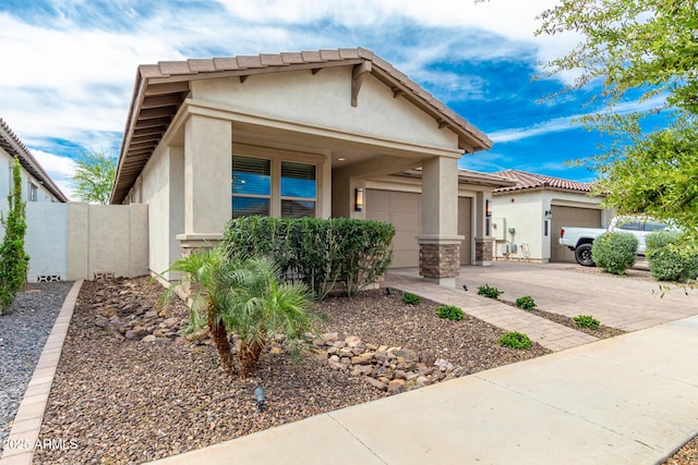 view of front of property with an attached garage, a tiled roof, concrete driveway, and stucco siding