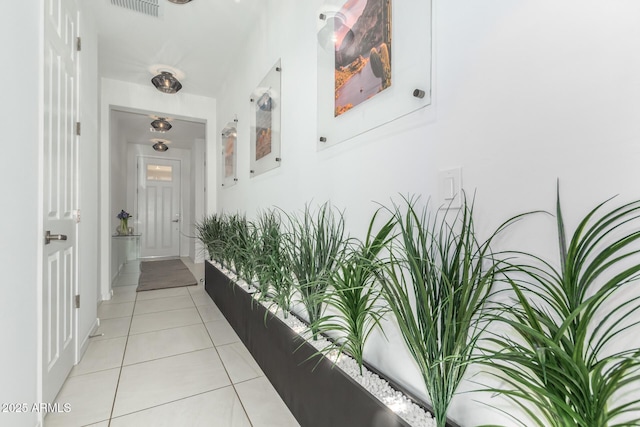 corridor with visible vents, baseboards, and light tile patterned floors