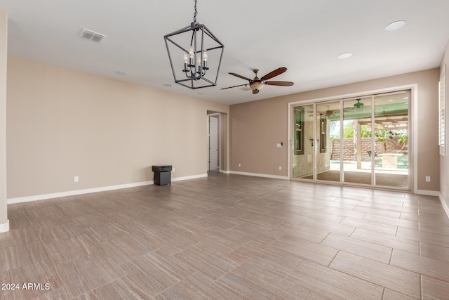 spare room featuring ceiling fan with notable chandelier