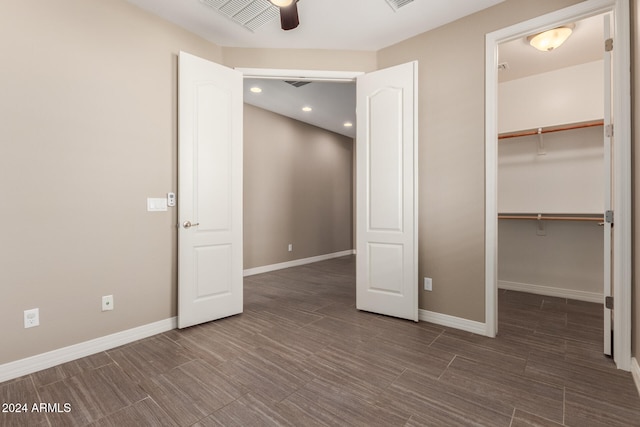 unfurnished bedroom featuring ceiling fan, a spacious closet, and a closet