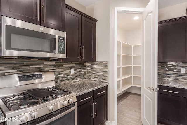 kitchen featuring dark brown cabinets, appliances with stainless steel finishes, and tasteful backsplash