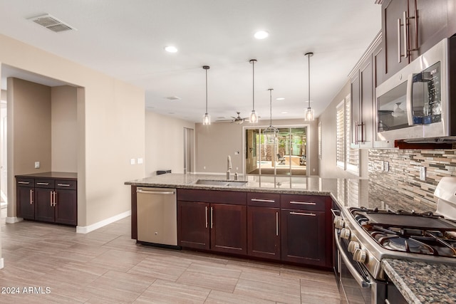 kitchen featuring appliances with stainless steel finishes, light stone counters, ceiling fan, sink, and pendant lighting