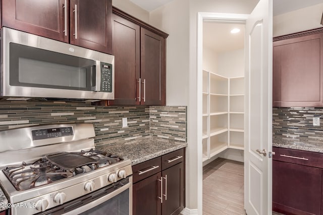 kitchen with appliances with stainless steel finishes, backsplash, and light stone counters