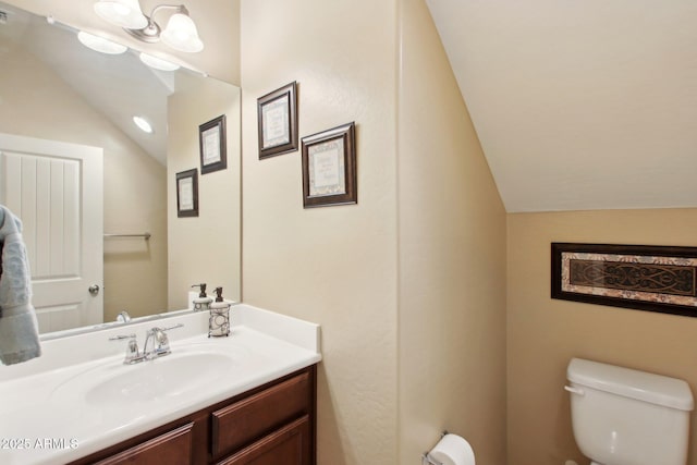 bathroom with vanity, toilet, and lofted ceiling