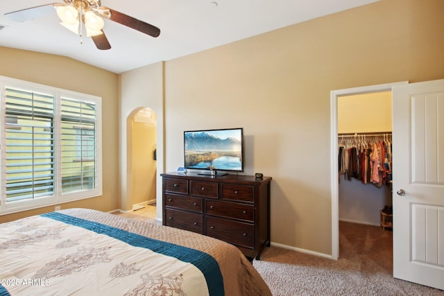 bedroom with ceiling fan, light colored carpet, lofted ceiling, a walk in closet, and a closet