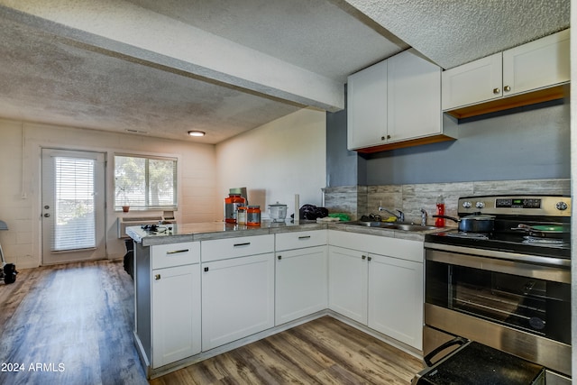 kitchen with light hardwood / wood-style flooring, kitchen peninsula, a textured ceiling, stainless steel electric stove, and white cabinetry