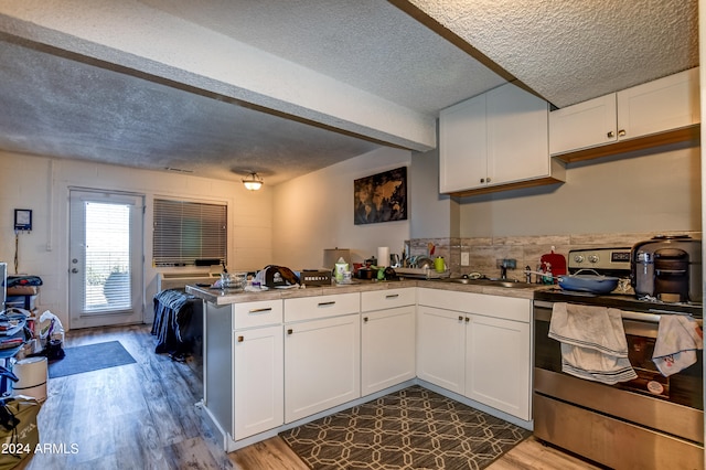 kitchen with a textured ceiling, kitchen peninsula, white cabinets, and stainless steel range with electric cooktop