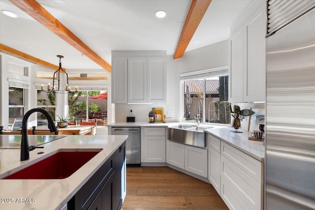 kitchen featuring pendant lighting, beam ceiling, white cabinets, and appliances with stainless steel finishes