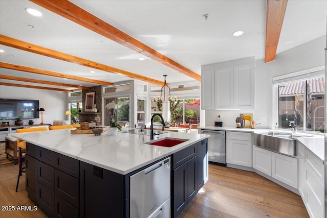 kitchen with a center island with sink, dishwasher, white cabinetry, and sink