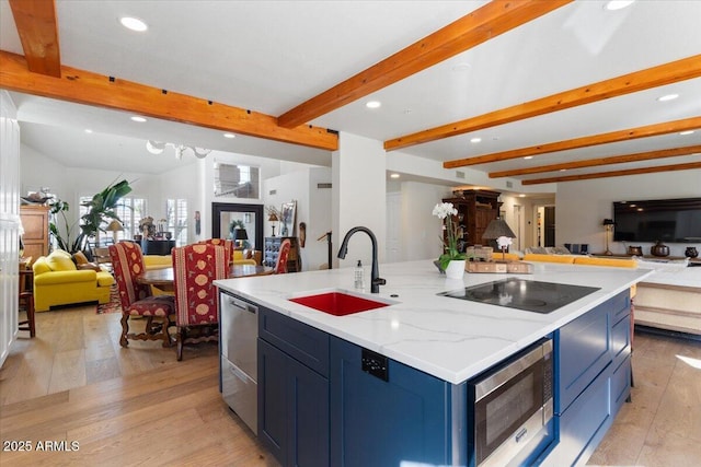 kitchen featuring sink, stainless steel appliances, blue cabinets, an island with sink, and light wood-type flooring